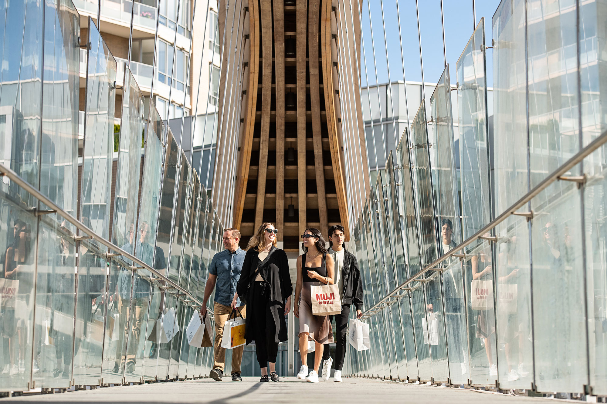 A group of young urban professionals walking across a modern looking overhead walkway